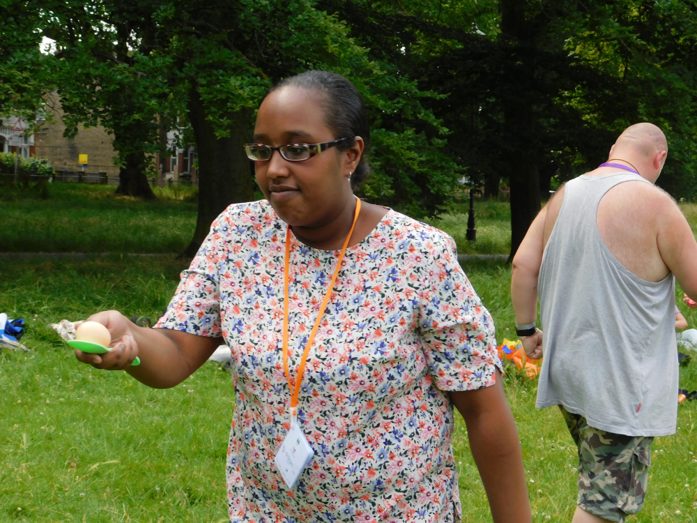 A lady carries an egg on a spoon in a sports day race