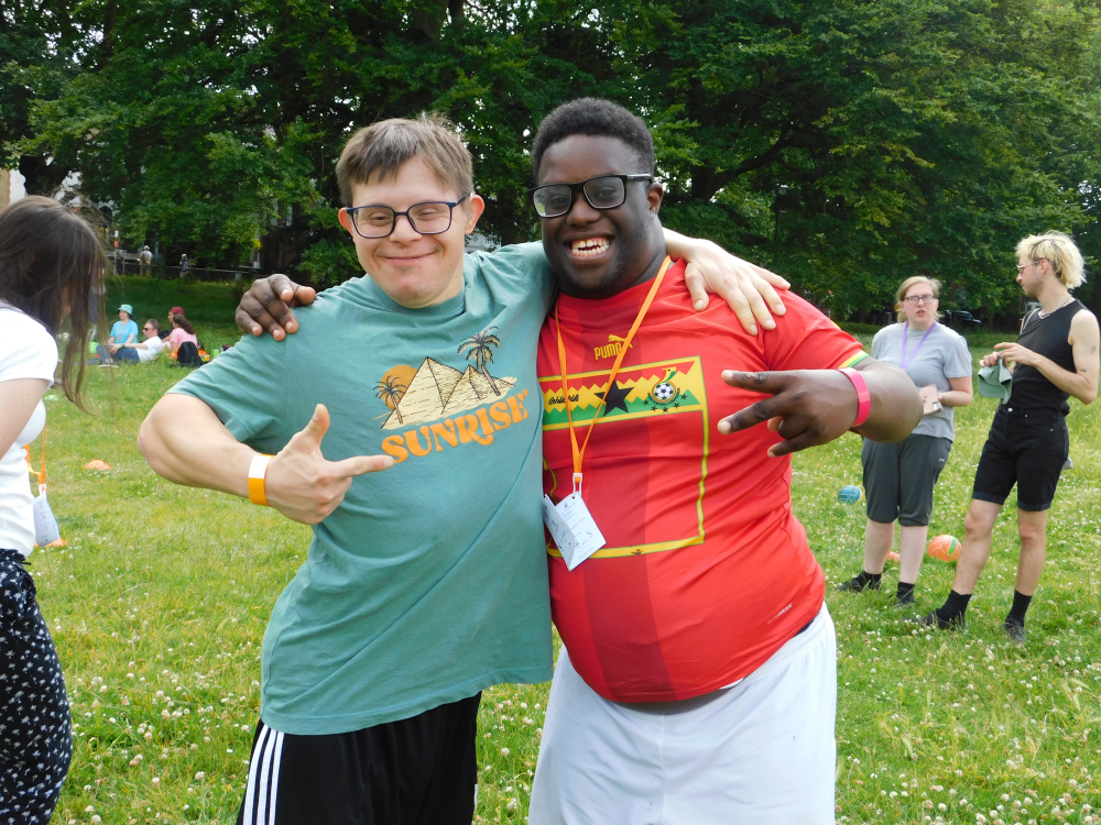 Two men stand smiling arm in arm