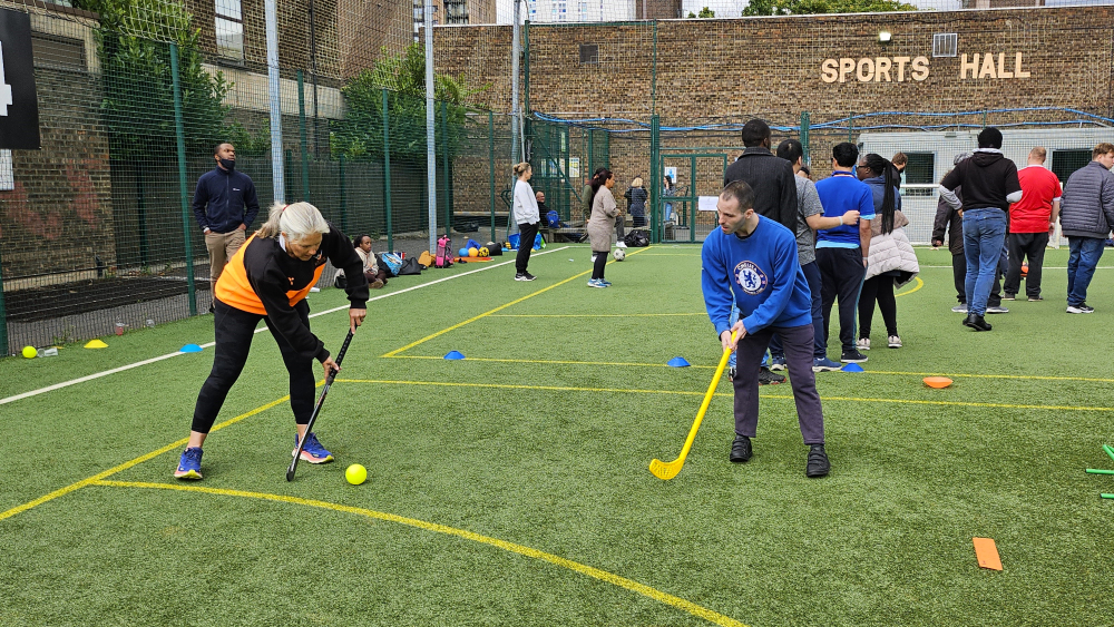 A group of people play hockey on an astroturf pitch