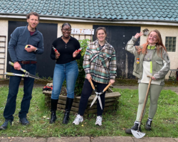 Four people stand with gardening equipment, ready to do some gardening