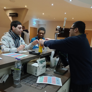 A man serves another man a drink at a bar and gives him his change