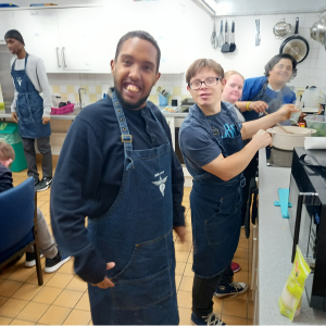 A group of students stand at a kitchen counter cooking on the stove.