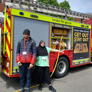 Two people stand next to a fire engine