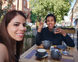 Two ladies sit outside at a cafe enjoying a cup of tea