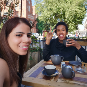 Two ladies sit outside at a cafe enjoying a cup of tea