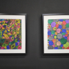 Two colourful abstract artworks hang on a black gallery wall