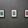 Two colourful abstract artworks hang on a black gallery wall