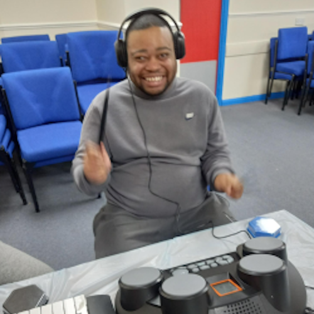 A man sits with headphones on in front of a mixing desk