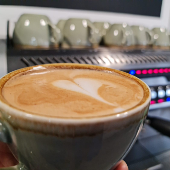 Close up of a cappuccino style cup of coffee in front of a professional coffee machine