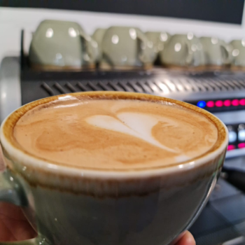 Close up of a latte with a barista coffee machine in the background