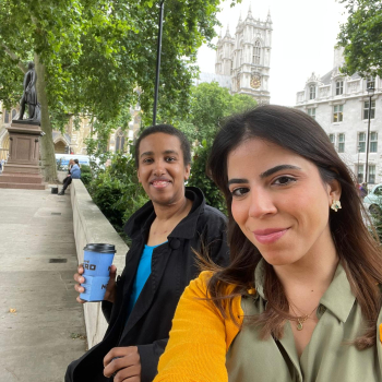 Two women sit on the banks of the Thames enjoying a coffee