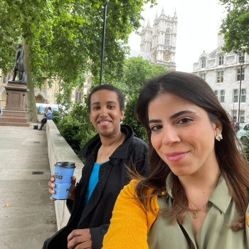 Two ladies sit on a wall taking a selfie