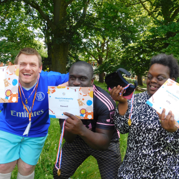 Three students smile and hold their certificates for taking part in sports day