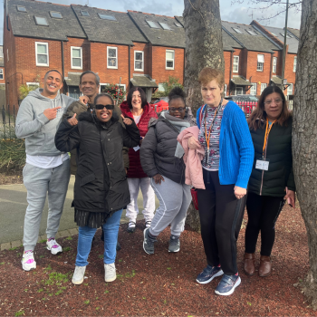 A group of students stand with a volunteer out on a trip