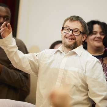 A man stands smiling with his arm up in the air