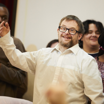 A man stands smiling at the camera with his arm in the air.